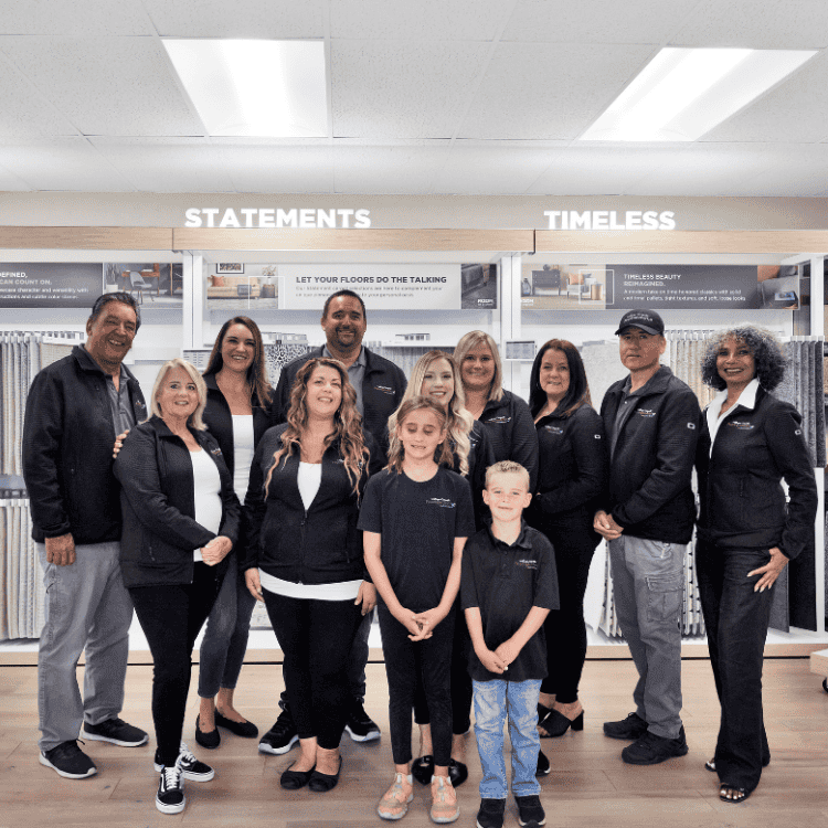 Flooring team standing in front of carpet flooring displays in store