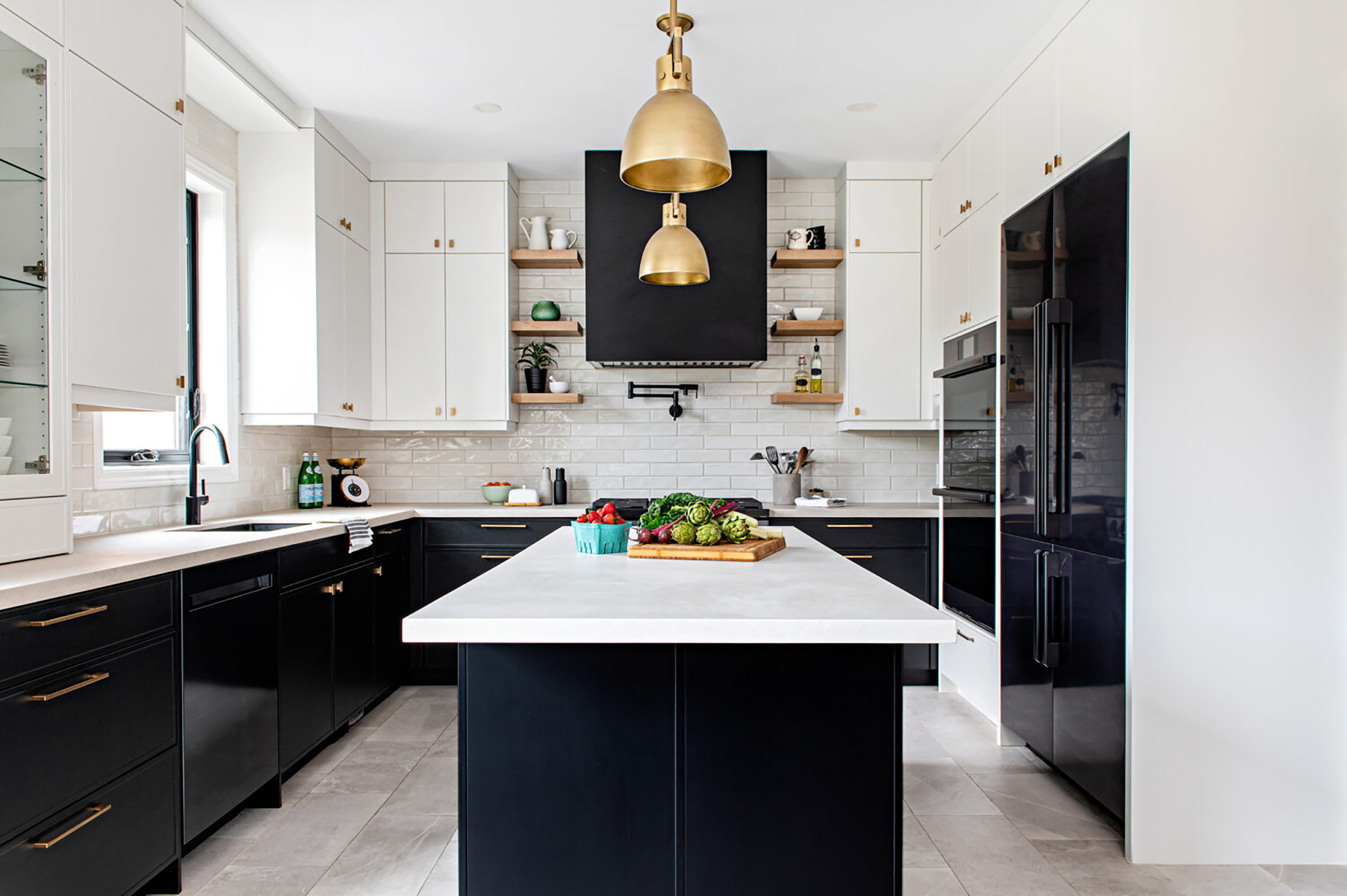 Contemporary black and white tones in a kitchen featuring tile floor, marble countertop, white cabinets, gold light fixtures.