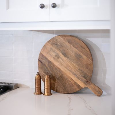 kitchen countertop with wood pizza peel and white cabinets