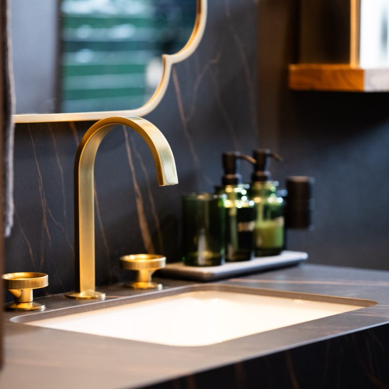 gold faucet and black accent wall and countertops