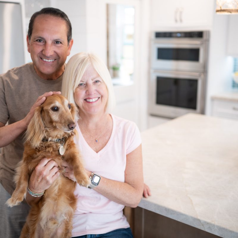 happy couple with pet dog in remodeled kitchen
